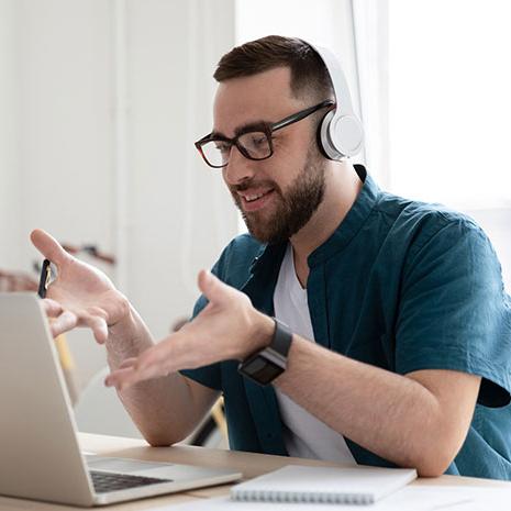 man with headphones speaking emphatically to computer