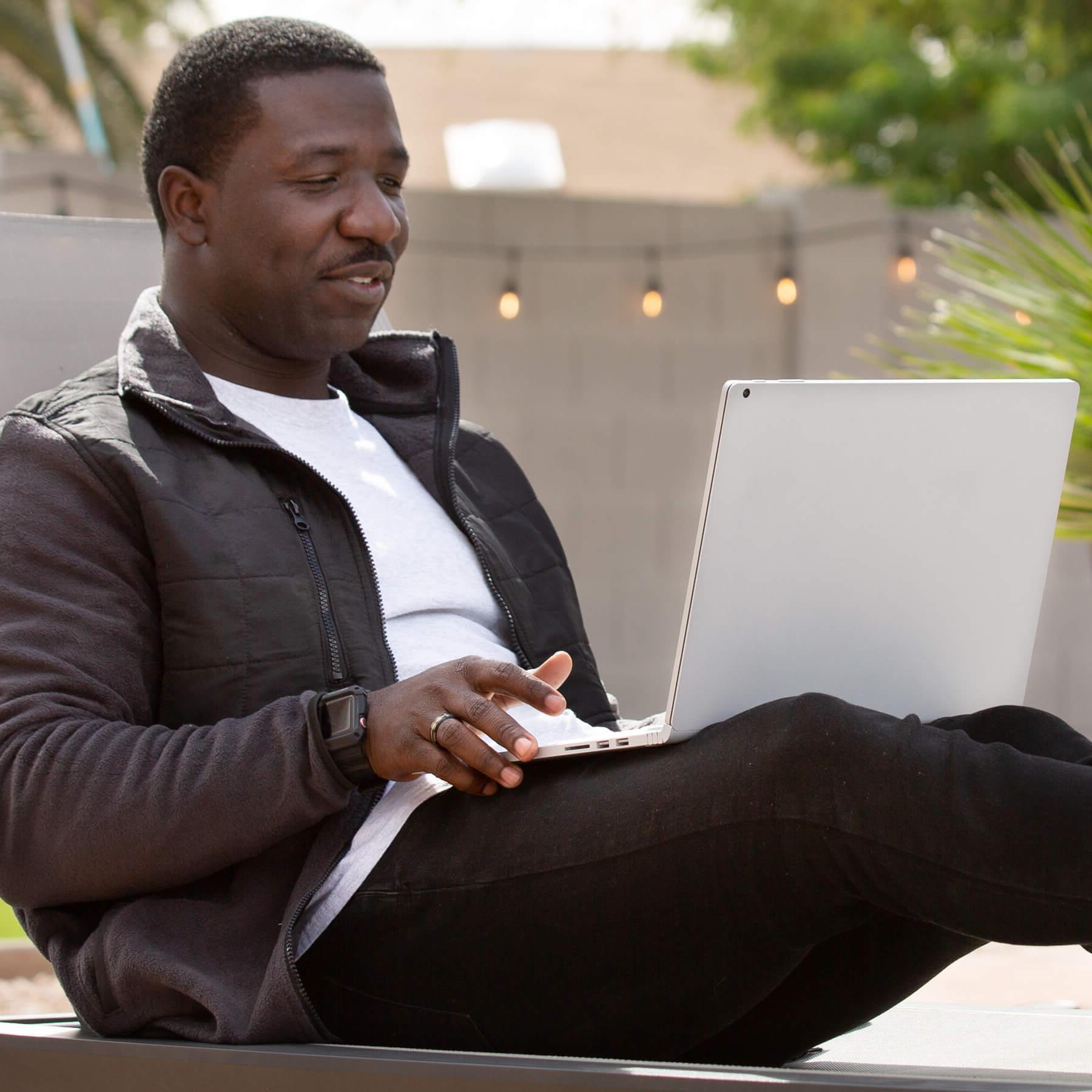 Jahmar Robinson studying on his laptop, outside on a patio